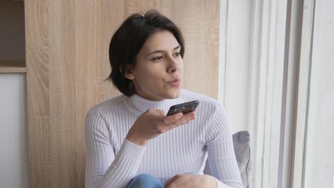 Eine Frau nimmt eine Sprachnachricht mit ihrem Handy auf