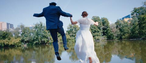 Ein Hochzeitspaar springt in einen See