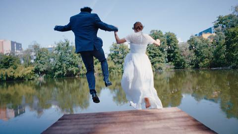 Ein Hochzeitspaar springt in einen See