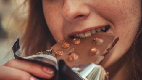Frau beißt in eine Tafel Schokolade